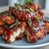 Crispy air fryer Korean fried chicken glazed with sweet-spicy gochujang sauce, garnished with sesame seeds.  