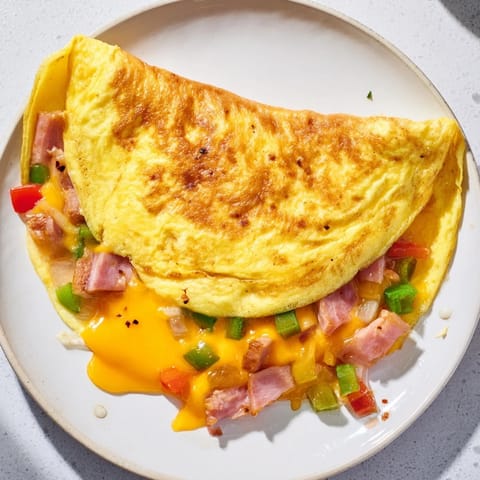Fluffy, folded Denver Omelet featuring a vibrant filling of ham, onions, and bell peppers in every bite.