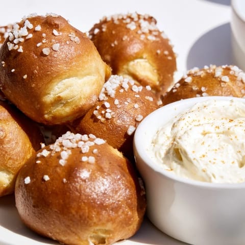 Soft pretzel bites, sprinkled with salt, ready to be dipped into creamy cheese.