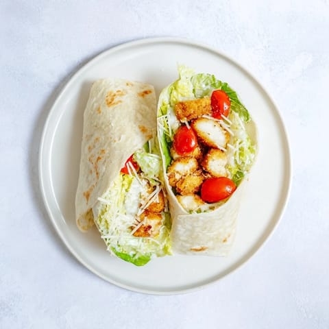 Crunchy panko-breaded chicken tossed in vibrant hot honey drizzle, layered over crisp romaine, cherry tomatoes, and Caesar dressing inside a soft wrap.