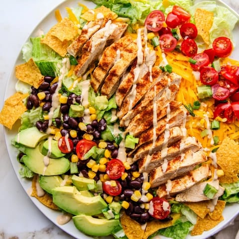 Crunchy Taco Chicken Salad features seasoned chicken, crisp romaine, beans, corn, and crushed shells on a bed of vibrant greens.