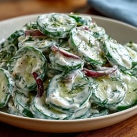 Creamy cucumber dill salad with crisp cucumbers and tangy dill dressing in a white serving bowl
